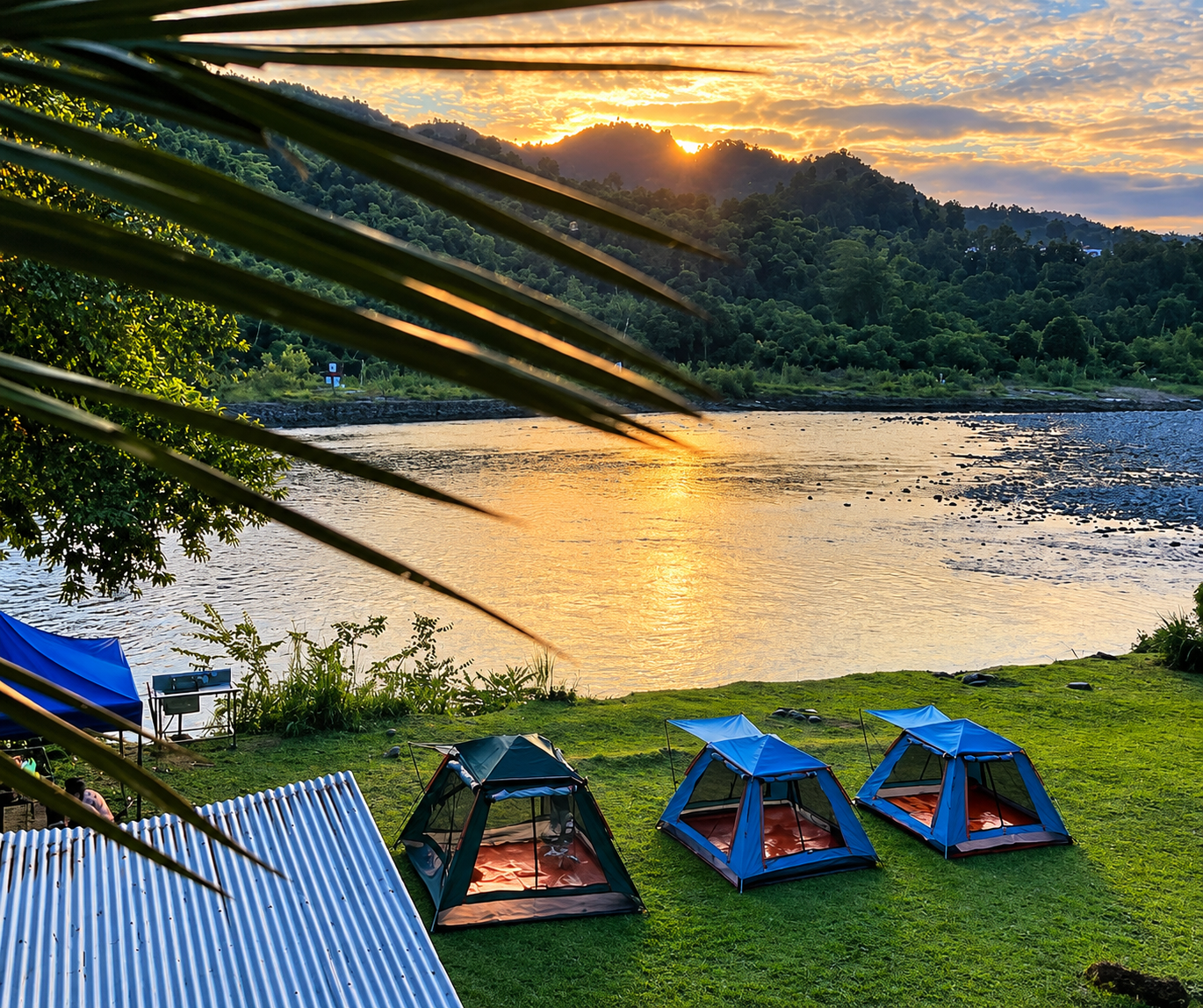 Khemah camping berhampiran sungai ketika matahari terbenam